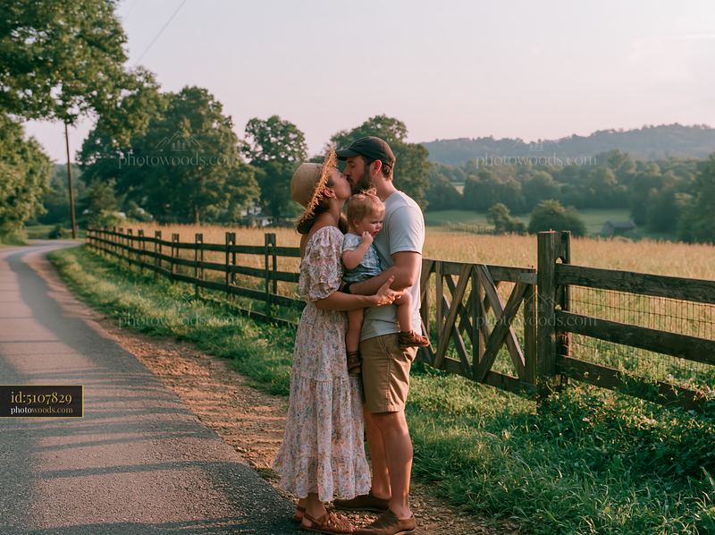 Couple with child sharing kiss on country road at sunset
