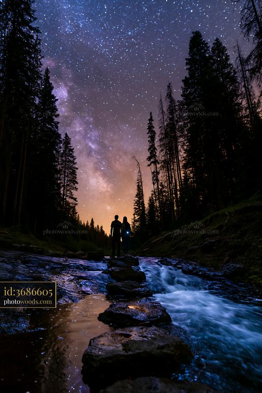 Couple under stars near a waterfall in the wilderness