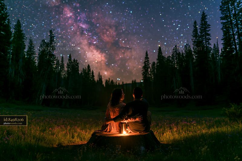 Couple views the Milky Way from a forest clearing at night
