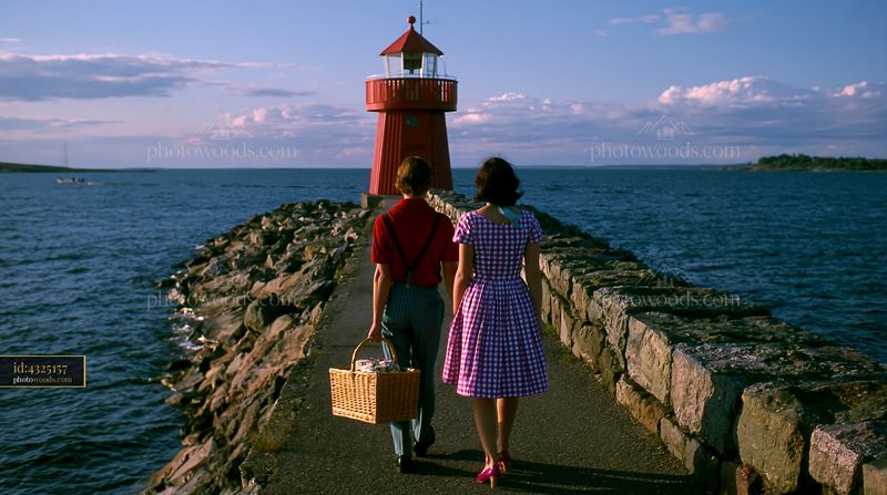Lighthouse with a couple exploring the coast at sunset
