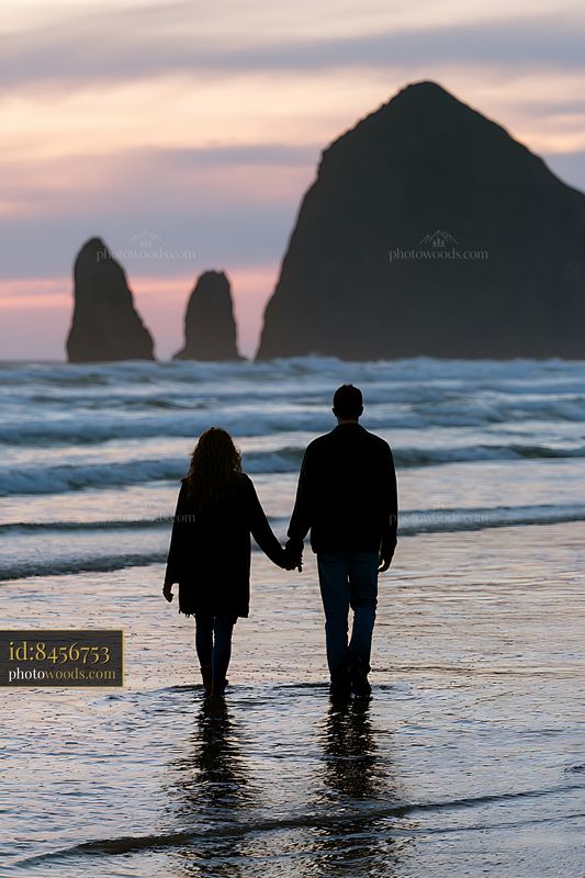 Couple walking hand in hand on the beach during sunset