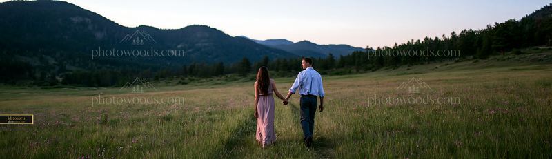 Couple walking along meadow path viewed from behind