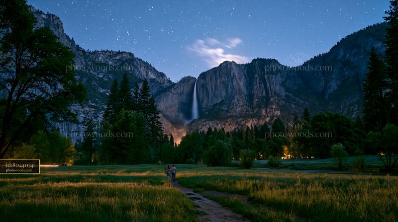 Couple under stars near a waterfall in a forest setting