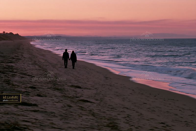 Couple walking together on quiet beach at dusk