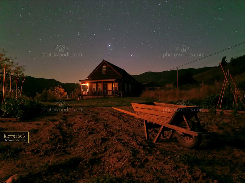Farmhouse beneath stars with rolling hills in background