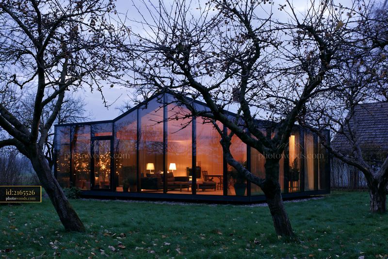 Modern empty garden house with glowing glass walls at dusk