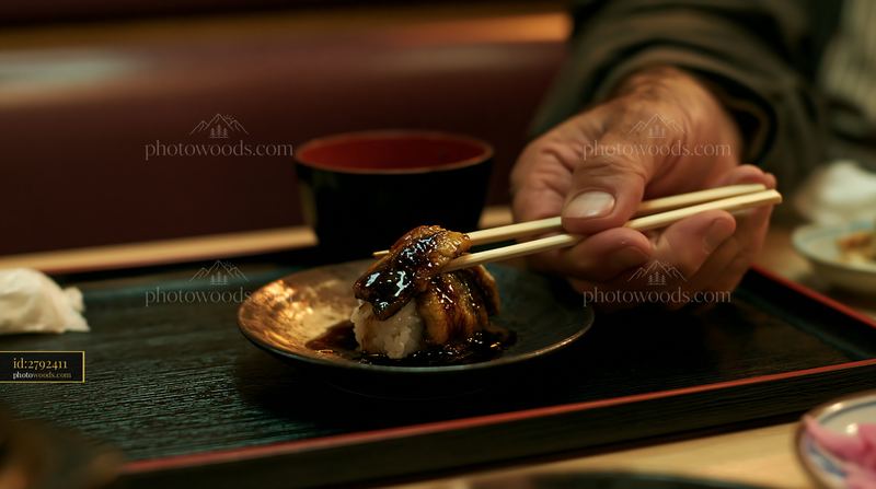 Eel sushi with sweet sauce served on a black plate