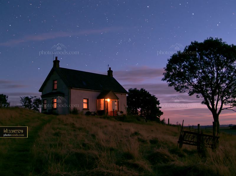 House beneath stars viewed from a field at night