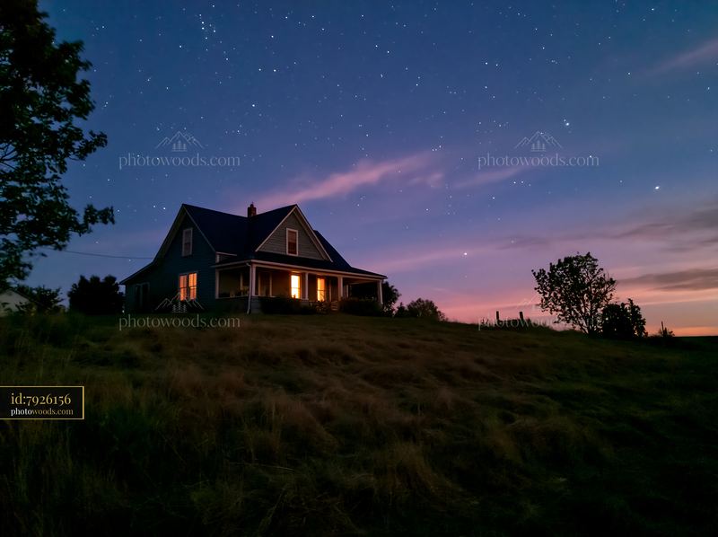 House beneath stars viewed from a field at dusk