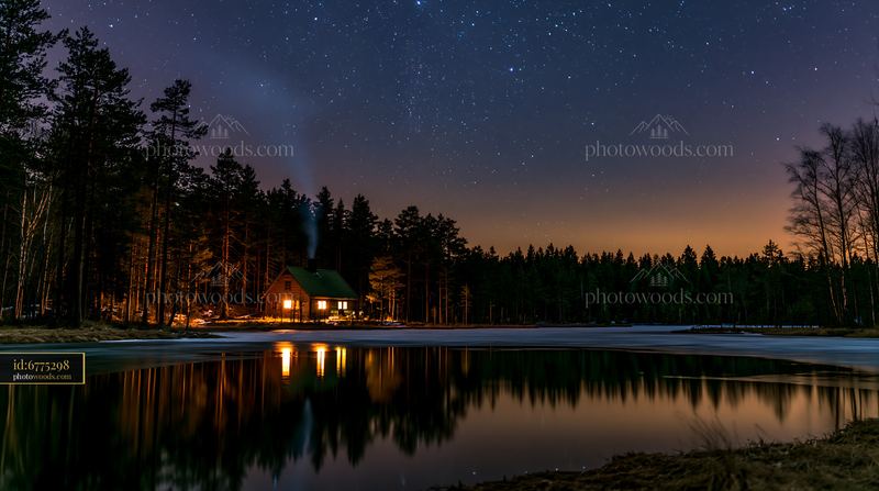 House with chimney smoke under stars in a winter landscape