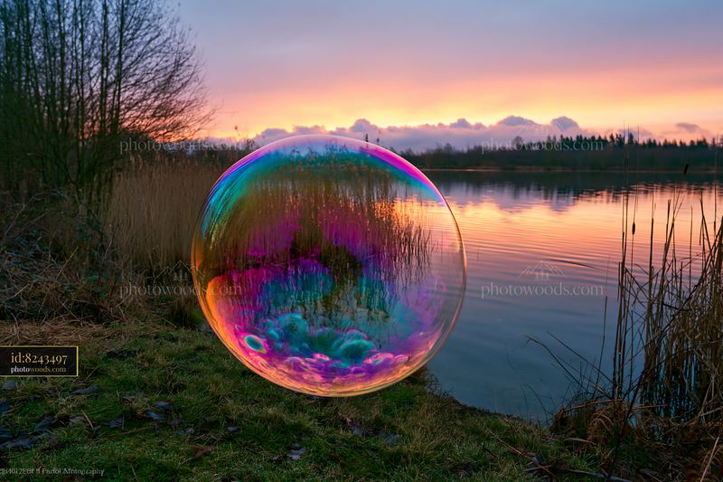 Colorful soap bubbles forming swirl by a lake during sunset