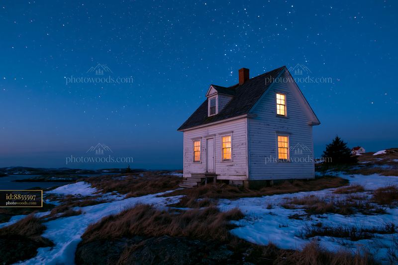 Lighthouse house under stars at night with glowing windows