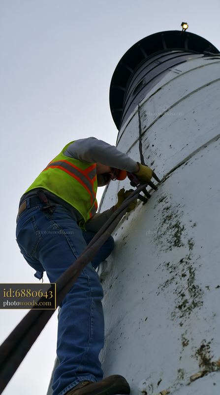 Lighthouse maintenance worker performs repairs on a tall structure