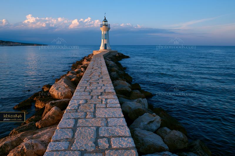 Minimalist lighthouse stands on a rocky pier by the sea