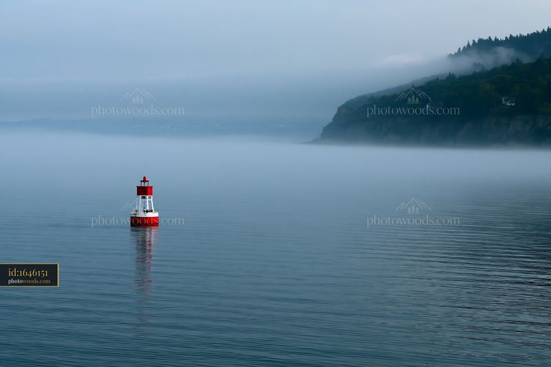 Coastline covered in sea fog with a lighthouse in the water