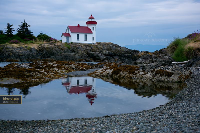Minimalist lighthouse seascape with rocky shore and reflection