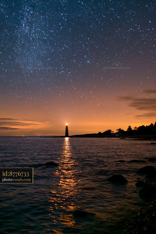 Starry night over a calm ocean with a lighthouse view