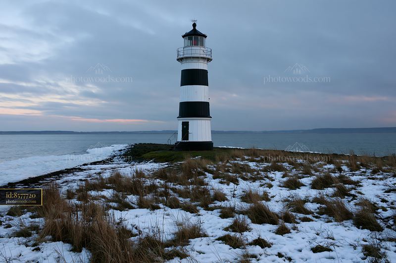Lighthouse with black and white stripes near the water during winter