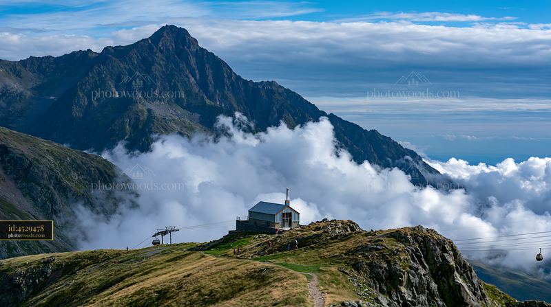 Dramatic clouds around alpine peaks with mountain hut