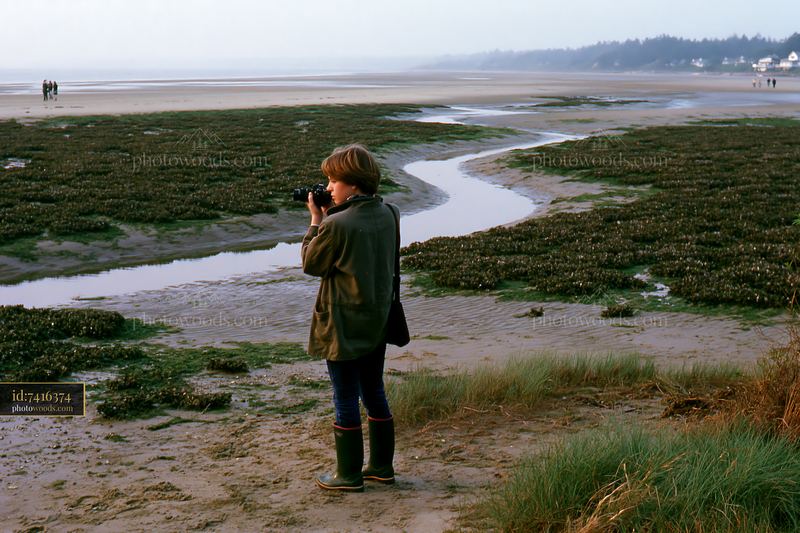 Photographer capturing coastline with oyster beds at low tide