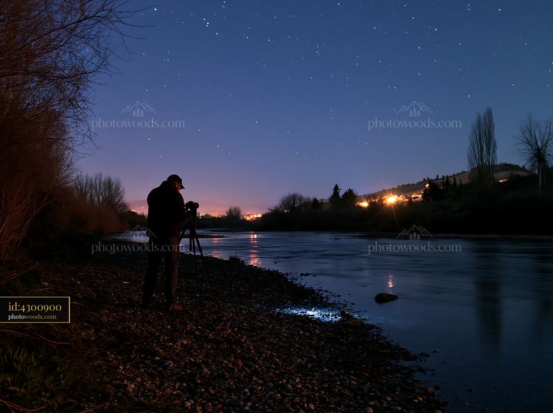 Photographer stands beside a riverbank under the stars