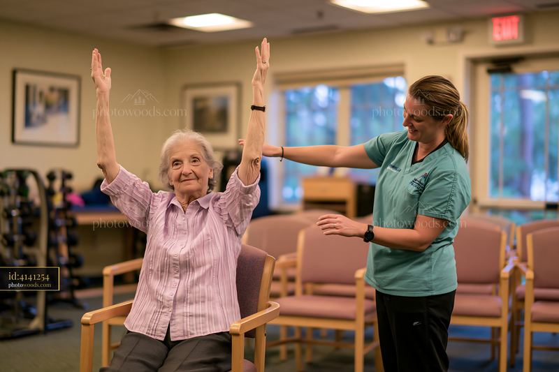 Physical therapist assisting elderly woman with exercises