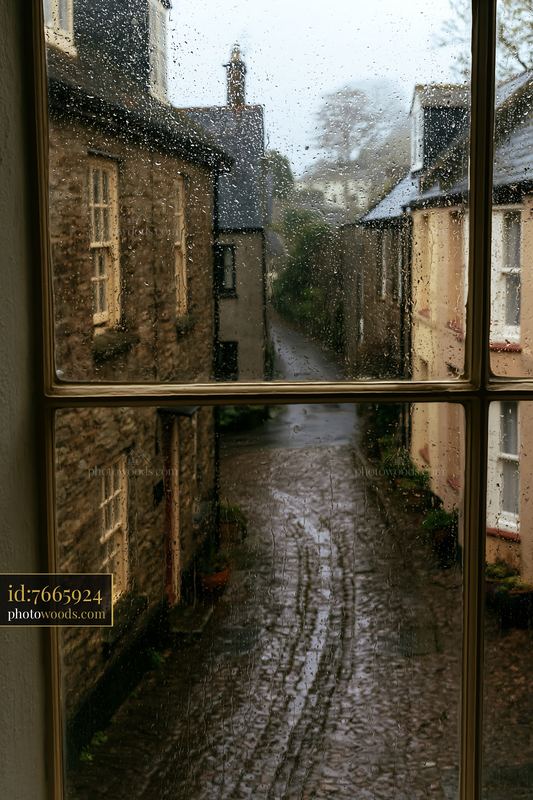 Rainy cottage exterior seen through wet glass creates a cozy view