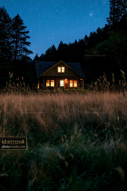 Remote mountain home surrounded by grass under night sky