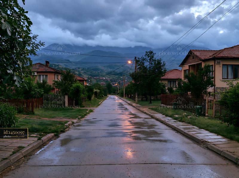 Thunderstorm over mountain range with wet road and houses