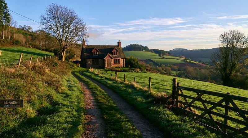 Rural cottage with chimney smoke in a green landscape