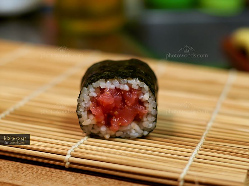 Single spicy tuna roll piece on a bamboo mat