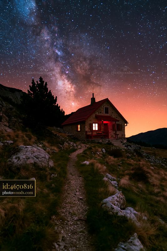 Remote house under Milky Way in mountain landscape at night