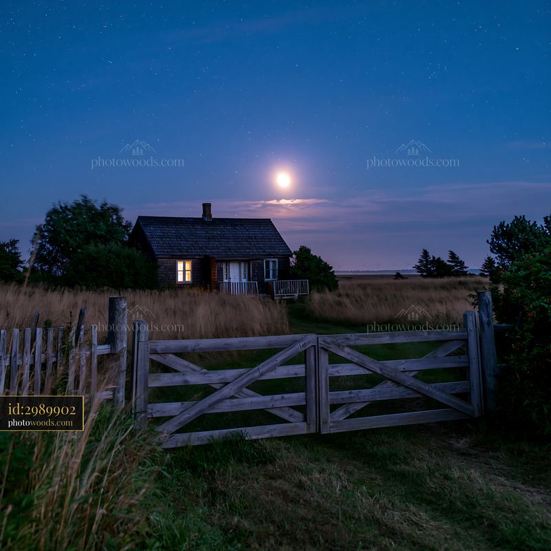 House beneath a full moon and stars in a quiet field