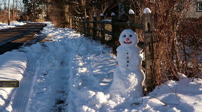 Snowman beside a wooden fence on a snowy path