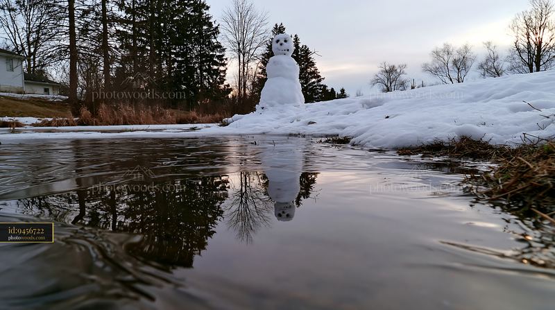 Snowman reflected in a frozen pond during winter