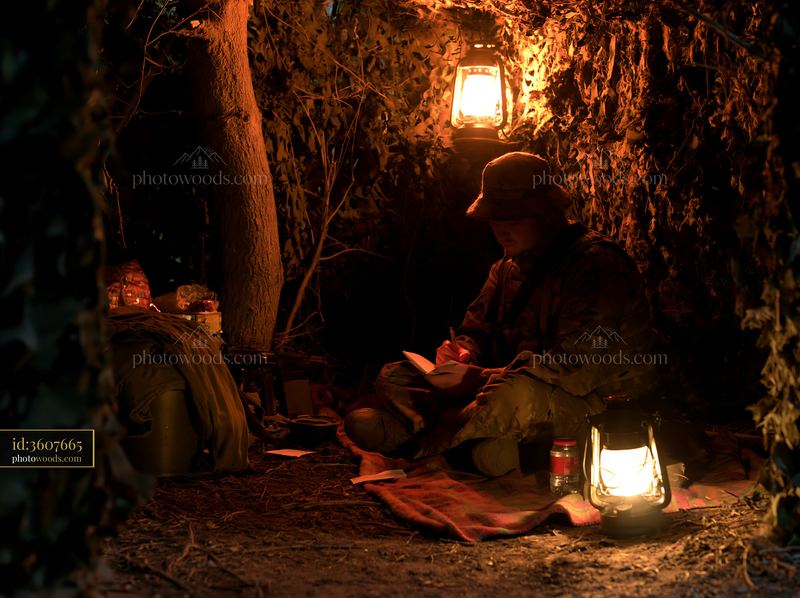 Soldier under camouflage netting in a military hideout