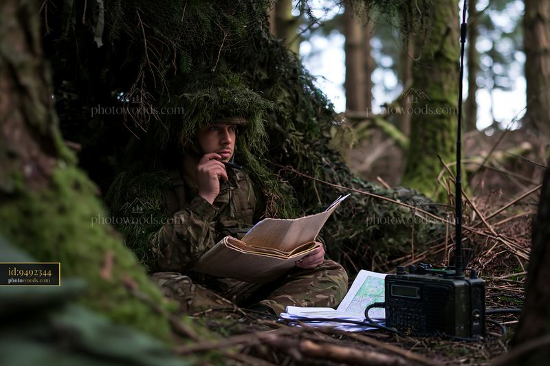 Soldier under camouflage netting in forest environment
