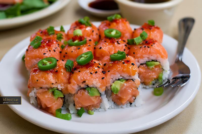 Spicy salmon sushi roll with chili on a white plate
