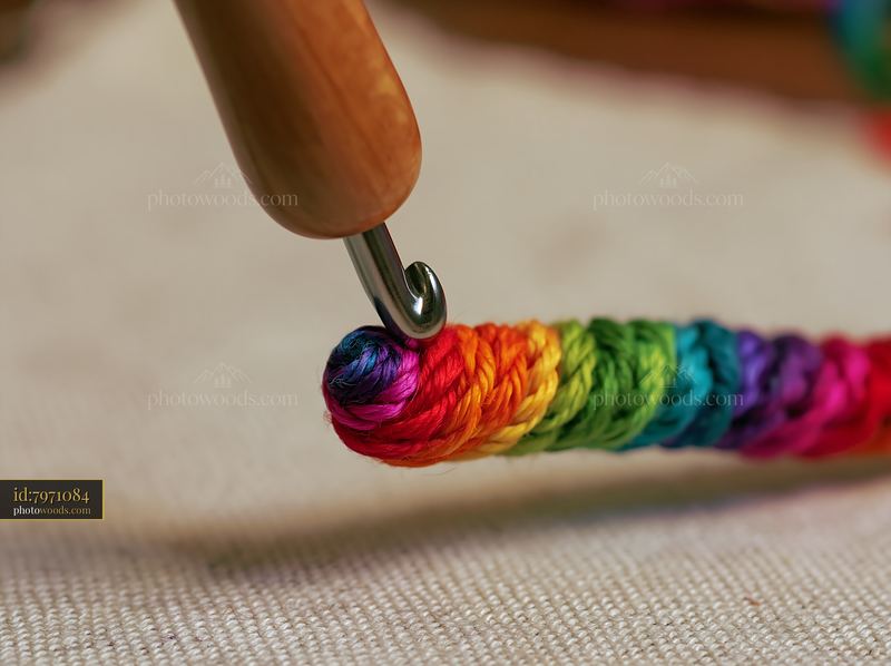Rainbow thread wound in spiral around a crochet hook
