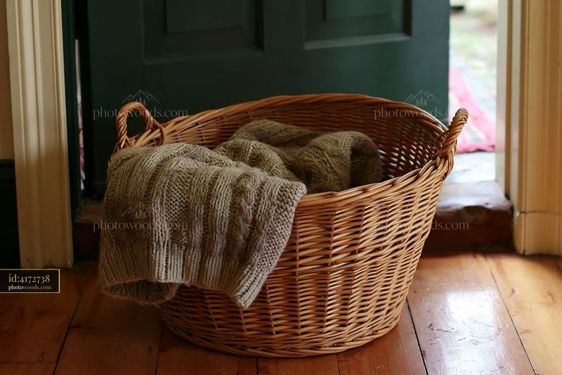 Wool sweater resting in a woven basket by a wooden door