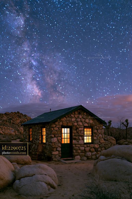 Desert home under starry sky with rocky landscape and mountains
