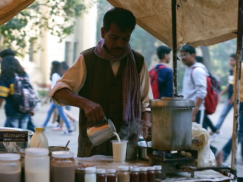 Street food vendor preparing tea with milk in busy market