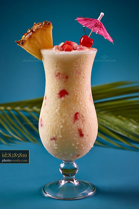 Tropical cocktail served in a tall glass with fruits and umbrella