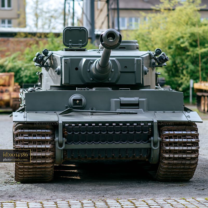 Tank parked in an industrial area with green trees