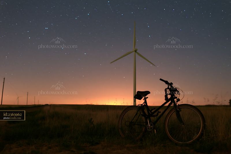 Starry night above a rural wind turbine with a bicycle nearby