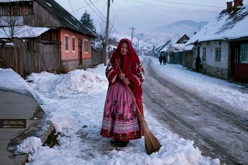 Folk costume woman standing in a snowy village street