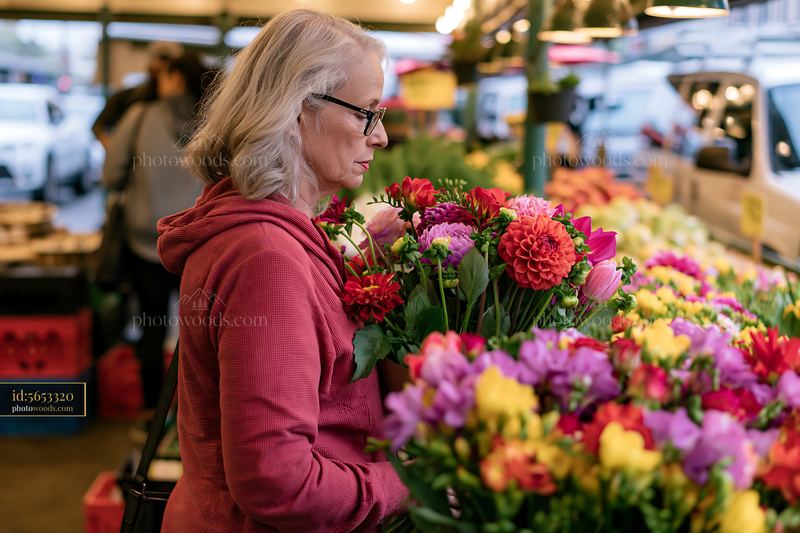 Woman shopping for mixed seasonal flowers at farmers market