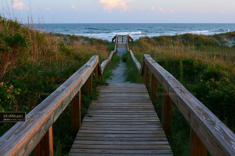 Wooden boardwalk leading to ocean beach at sunset