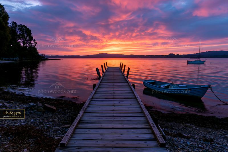 Sunset over a dock and shoreline with a boat in the foreground
