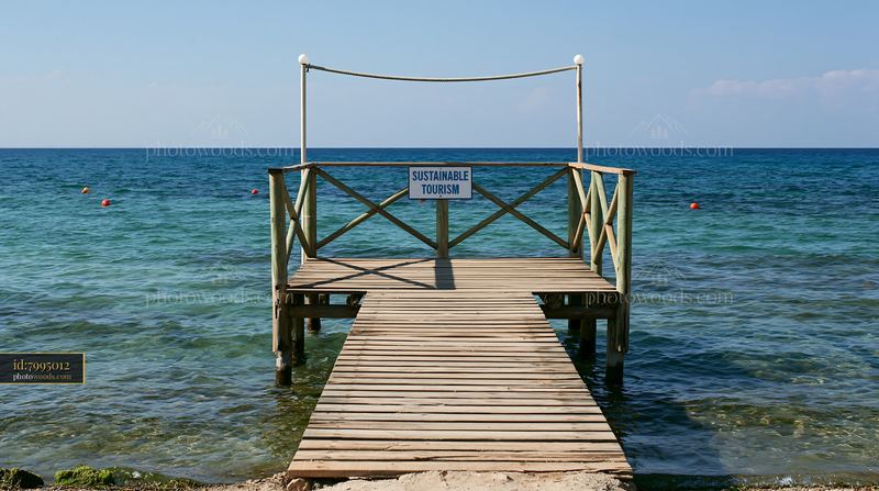 Coastline with sustainable tourism sign at wooden pier